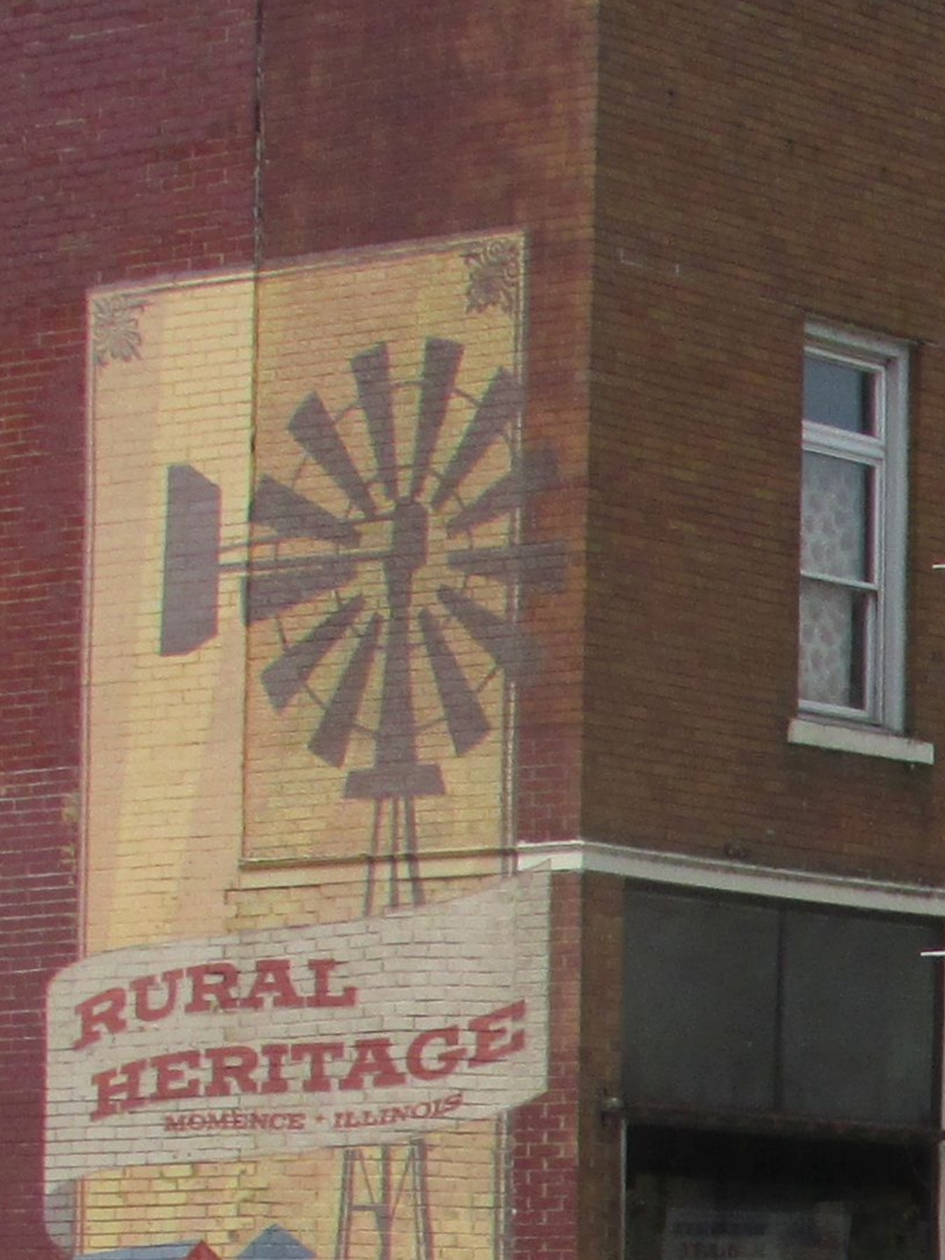 The painted Rural Heritage windmill mural on a brick corner building in Momence